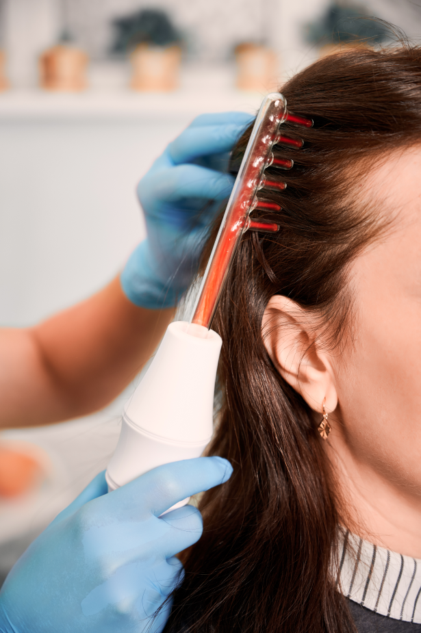 Hair specialist performing laser scalp therapy on a female client at Catara Med Spa in Algonquin, IL to support hair growth and scalp health.