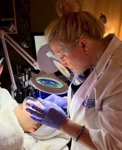 licensed aesthetician performing a facial treatment at catara med spa in algonquin il using magnifying lamp and precision techniques