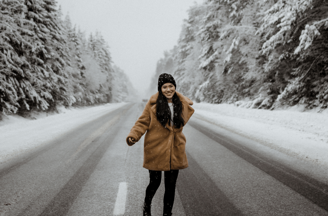 Woman walking on a snowy road in winter, dressed warmly. Symbolic of protecting your skin from weather in cold conditions.